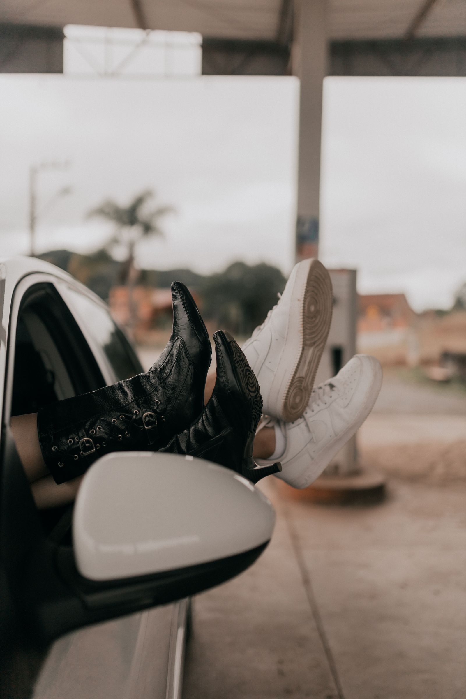 Close-up of diverse footwear hanging out of a car window showcasing fashion and relaxation.