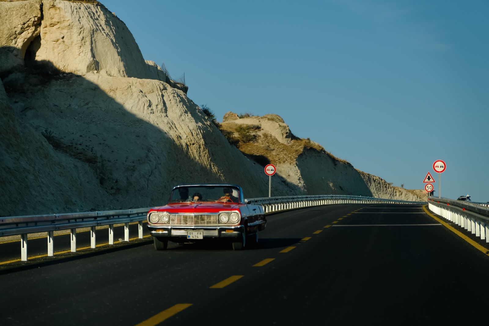 Red convertible driving along a scenic coastal highway