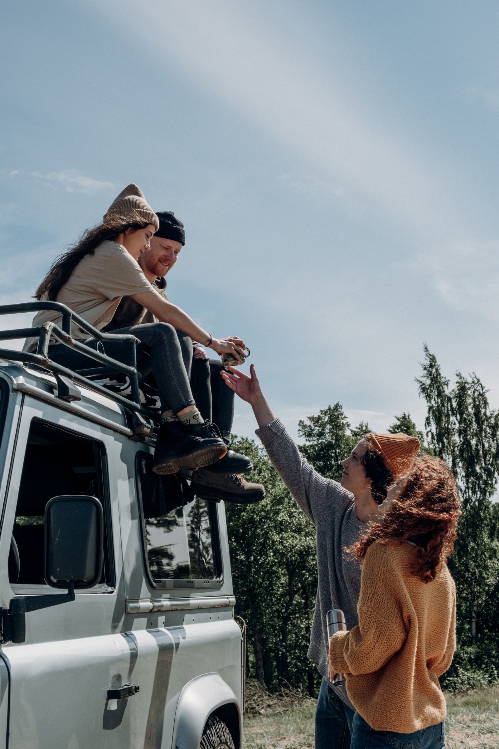 Group of friends enjoying a summer road trip with an SUV, relaxing outdoors and having fun.